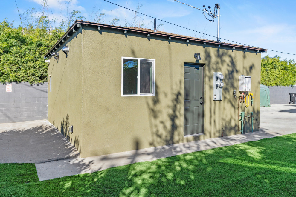 Cette image montre une façade de Tiny House verte minimaliste en briques peintes et bardeaux de taille moyenne et de plain-pied avec un toit plat, un toit en shingle et un toit gris.
