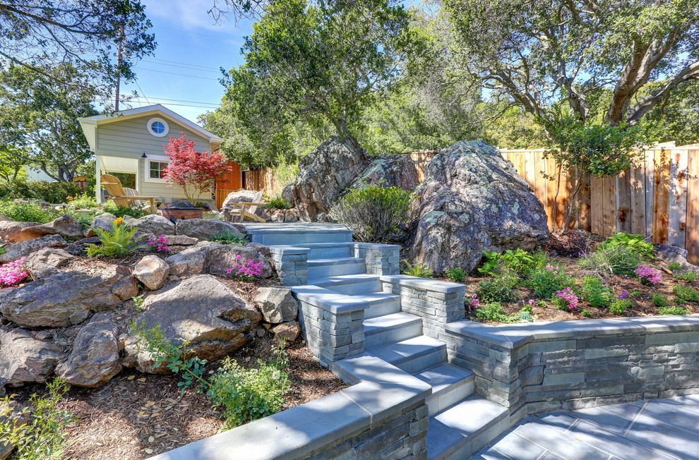 Inspiration for a large transitional backyard partial sun formal garden for spring in San Francisco with a retaining wall and natural stone pavers.