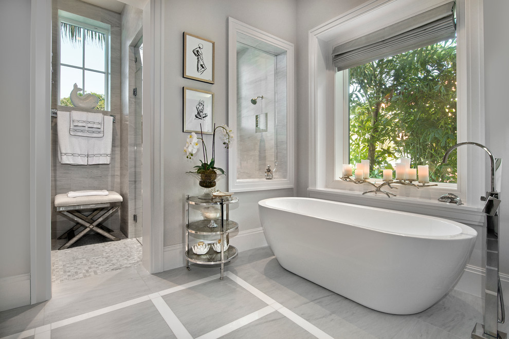 Design ideas for a mid-sized transitional master bathroom in Miami with a freestanding tub, gray tile, grey walls, an alcove shower and a hinged shower door.