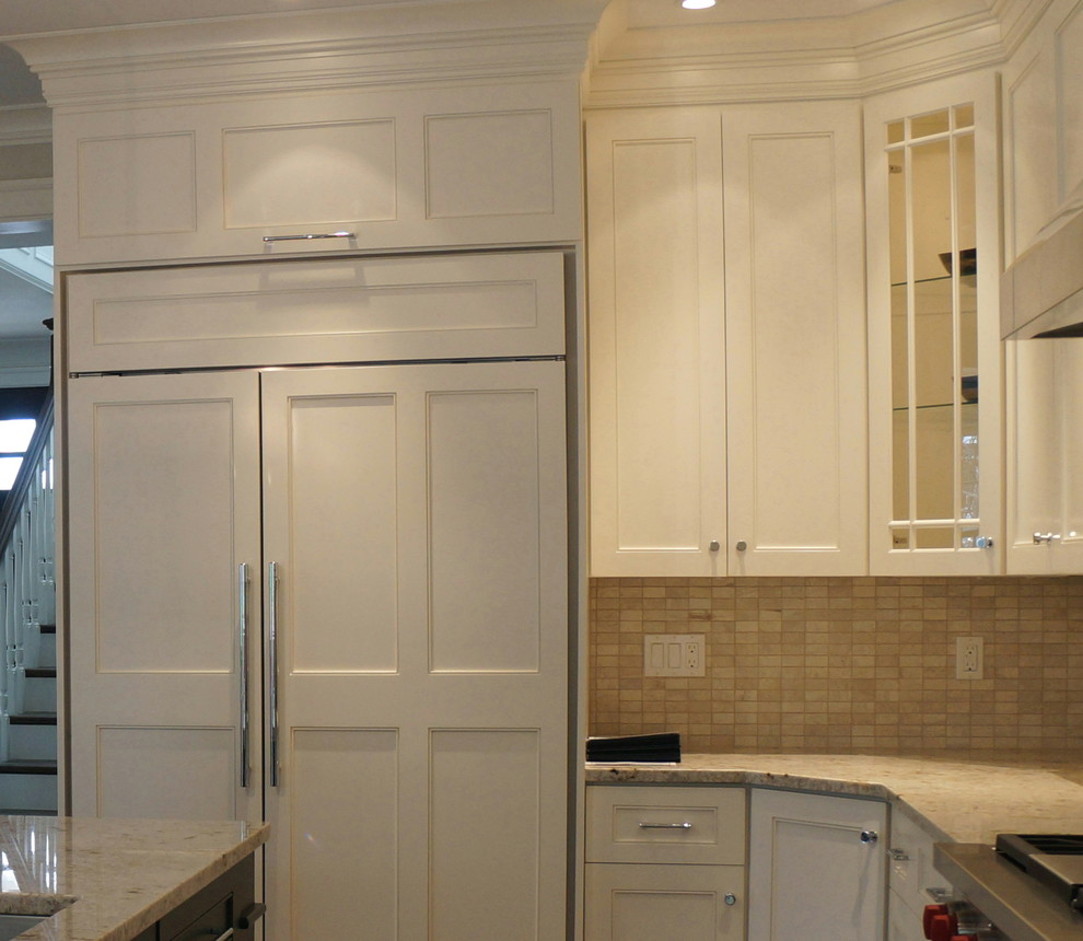 Example of a mid-sized transitional l-shaped travertine floor eat-in kitchen design in Boston with recessed-panel cabinets, white cabinets, beige backsplash, paneled appliances, an undermount sink, marble countertops, subway tile backsplash and an island