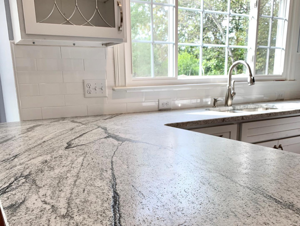 Inspiration for a large transitional l-shaped dark wood floor and brown floor eat-in kitchen remodel with a double-bowl sink, shaker cabinets, white cabinets, granite countertops, white backsplash, ceramic backsplash, stainless steel appliances, a peninsula and white countertops