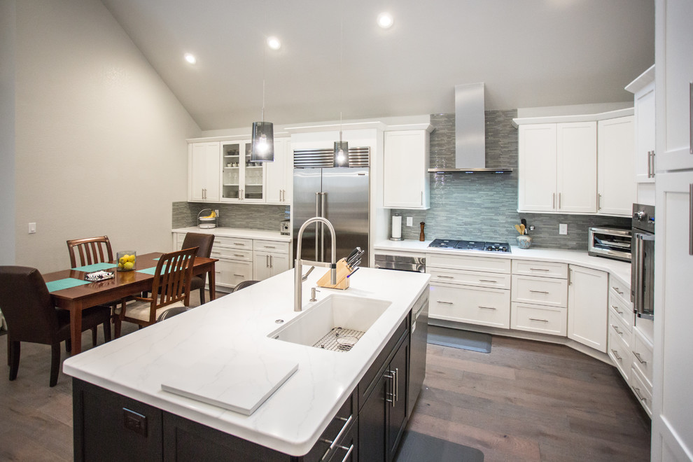 Inspiration for a large contemporary l-shaped eat-in kitchen in Sacramento with a single-bowl sink, shaker cabinets, white cabinets, quartz benchtops, grey splashback, glass tile splashback, stainless steel appliances, medium hardwood floors, with island and grey floor.
