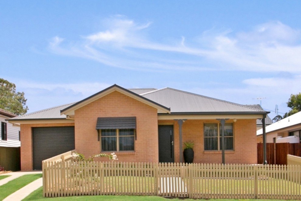 Photo of a small traditional one-storey brick red house exterior in Newcastle - Maitland with a gable roof and a metal roof.