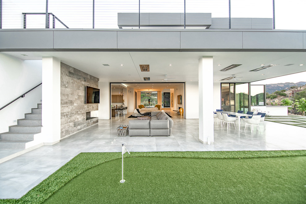 This is an example of an expansive contemporary backyard patio in Los Angeles with tile and a roof extension.