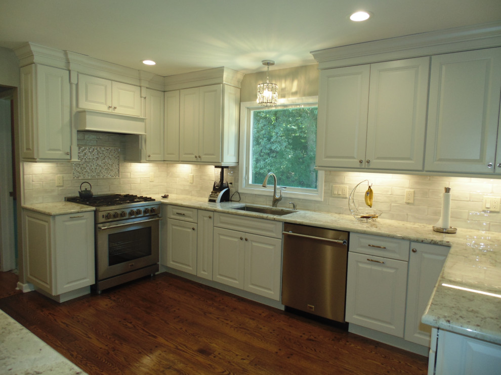 Mid-sized transitional u-shaped medium tone wood floor and brown floor eat-in kitchen photo with an undermount sink, raised-panel cabinets, white cabinets, granite countertops, white backsplash, subway tile backsplash, stainless steel appliances, no island and gray countertops