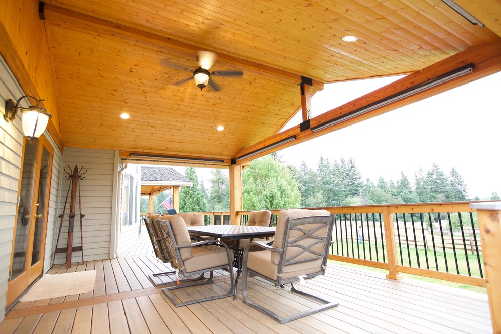 Inspiration for a large rustic backyard deck remodel in Seattle with a roof extension and a fire pit