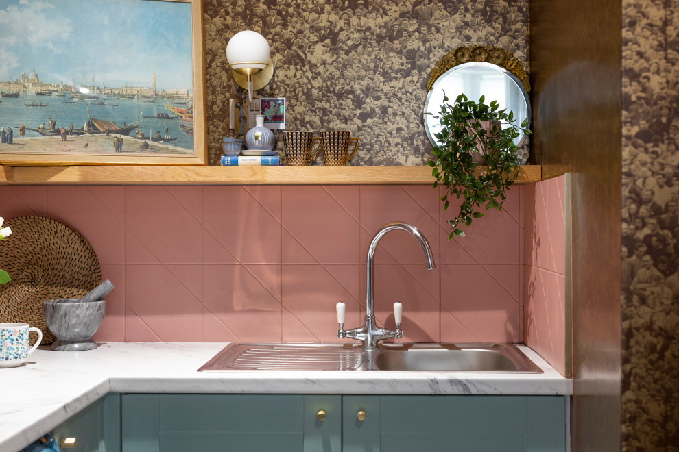 Small eclectic l-shaped open plan kitchen in Edinburgh with a single-bowl sink, shaker cabinets, blue cabinets, laminate benchtops, pink splashback, ceramic splashback, stainless steel appliances, vinyl floors, no island, multi-coloured floor and grey benchtop.