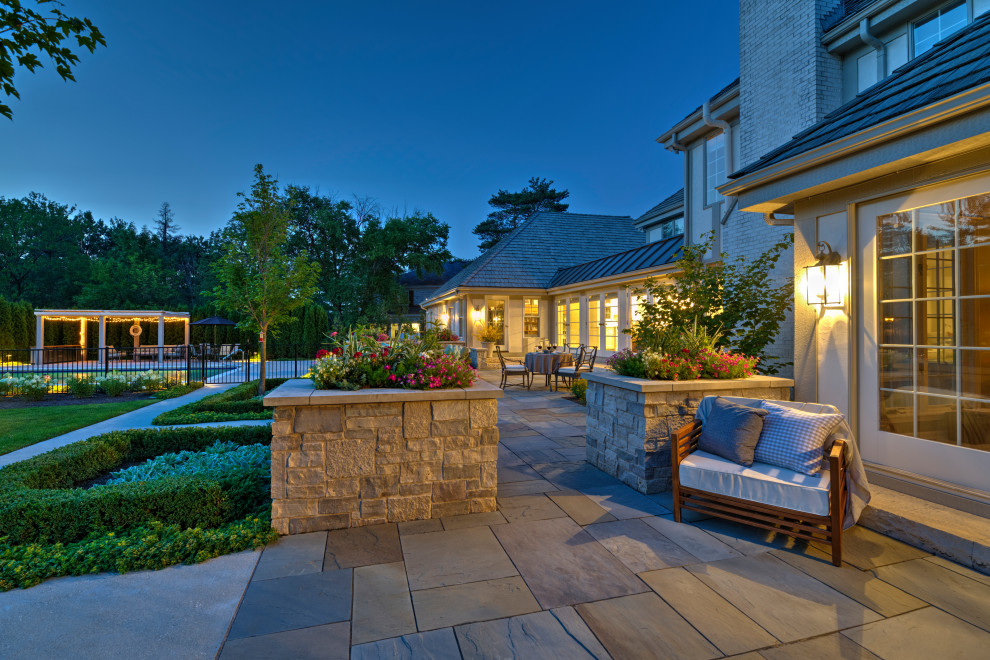 Design ideas for a large traditional backyard patio in Chicago with natural stone pavers and no cover.