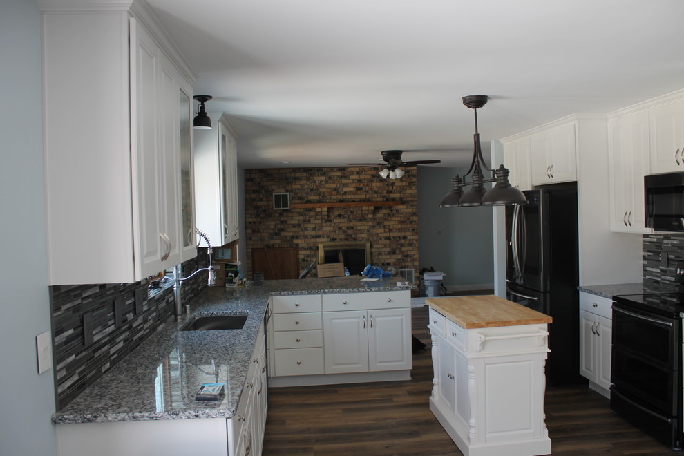 Mid-sized transitional u-shaped dark wood floor and brown floor kitchen photo with an undermount sink, raised-panel cabinets, white cabinets, granite countertops, multicolored backsplash, matchstick tile backsplash, stainless steel appliances and an island