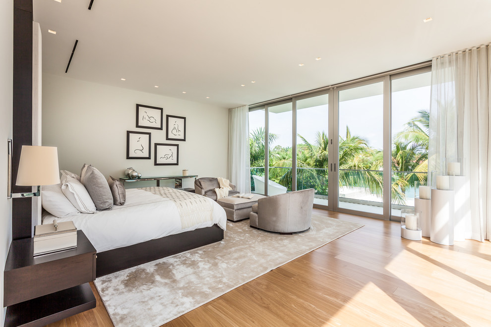 Design ideas for a contemporary bedroom in Miami with white walls and medium hardwood floors.