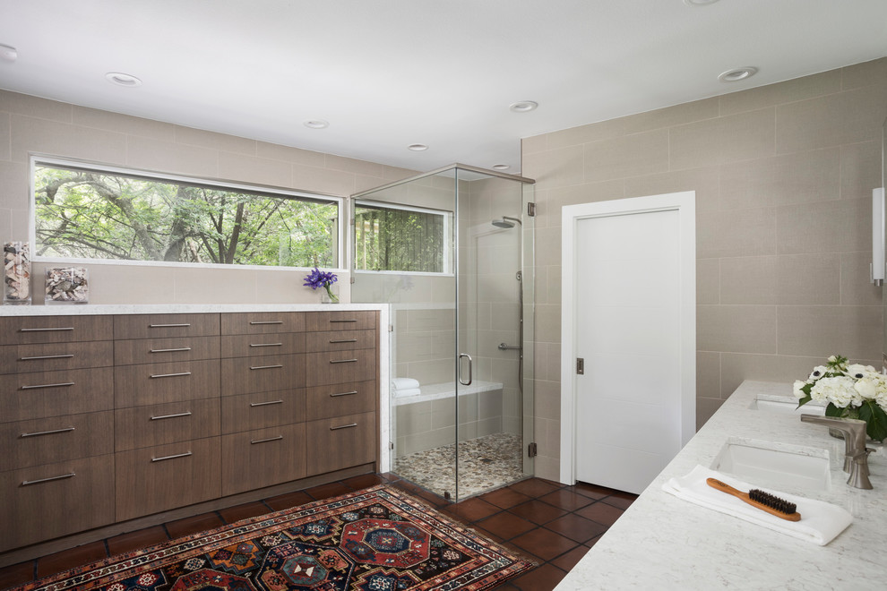 Photo of a mid-sized contemporary bathroom in Austin with flat-panel cabinets, brown cabinets, a corner shower, gray tile, porcelain tile, grey walls, terra-cotta floors, an undermount sink, quartzite benchtops, brown floor and a hinged shower door.