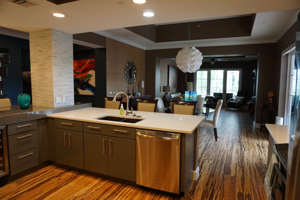 Inspiration for a mid-sized modern open plan kitchen in Tampa with an undermount sink, glass-front cabinets, grey cabinets, recycled glass benchtops, grey splashback, matchstick tile splashback, stainless steel appliances, vinyl floors, a peninsula and brown floor.