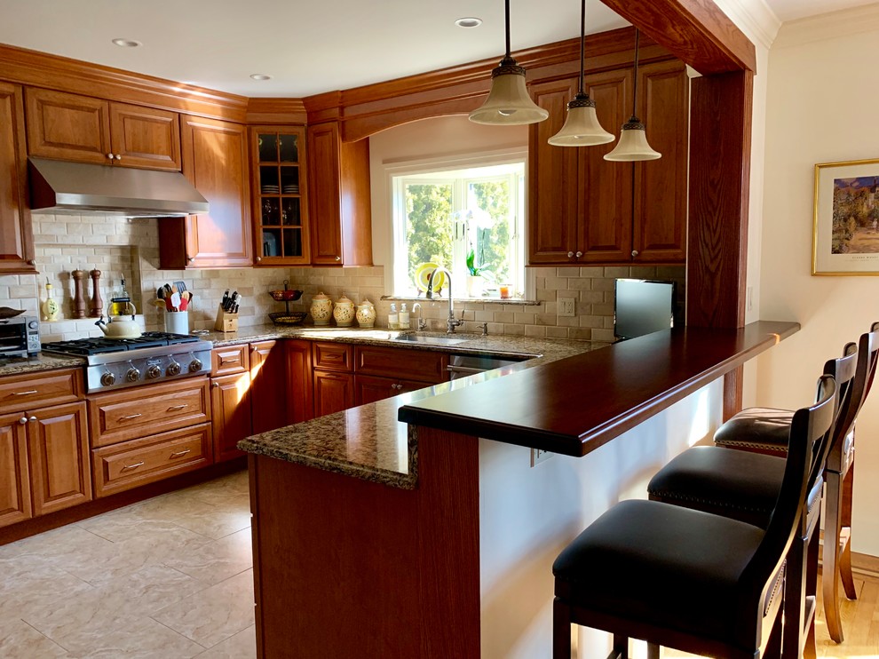 Mid-sized traditional eat-in kitchen in New York with a drop-in sink, brown cabinets, quartzite benchtops, beige splashback, stone tile splashback, stainless steel appliances, ceramic floors, no island, beige floor and brown benchtop.