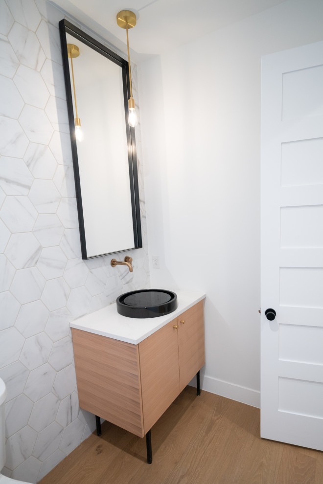 Design ideas for a mid-sized modern powder room in Denver with flat-panel cabinets, light wood cabinets, a two-piece toilet, white tile, porcelain tile, white walls, medium hardwood floors, a vessel sink, quartzite benchtops, brown floor, white benchtops and a freestanding vanity.