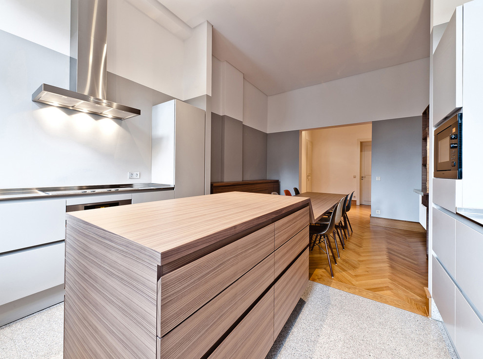 Inspiration for a mid-sized contemporary galley open plan kitchen in Frankfurt with an integrated sink, flat-panel cabinets, grey cabinets, stainless steel benchtops, stainless steel appliances, marble floors and with island.