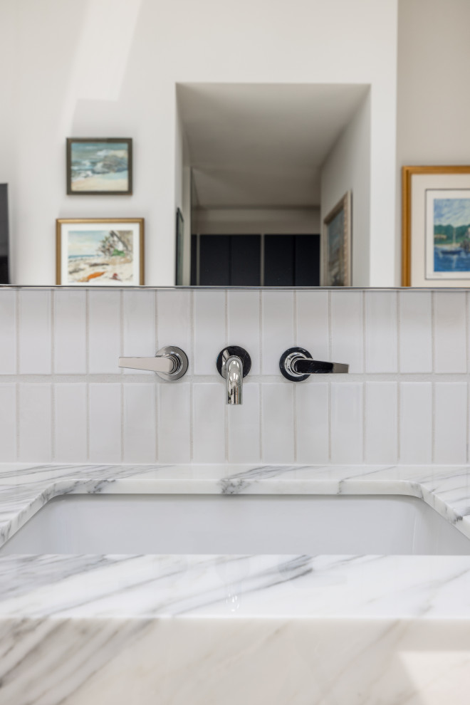 Exempel på ett mycket stort modernt vit vitt en-suite badrum, med släta luckor, skåp i ljust trä, en jacuzzi, en kantlös dusch, en bidé, vit kakel, tunnelbanekakel, vita väggar, kalkstensgolv, ett konsol handfat, marmorbänkskiva, beiget golv och dusch med gångjärnsdörr