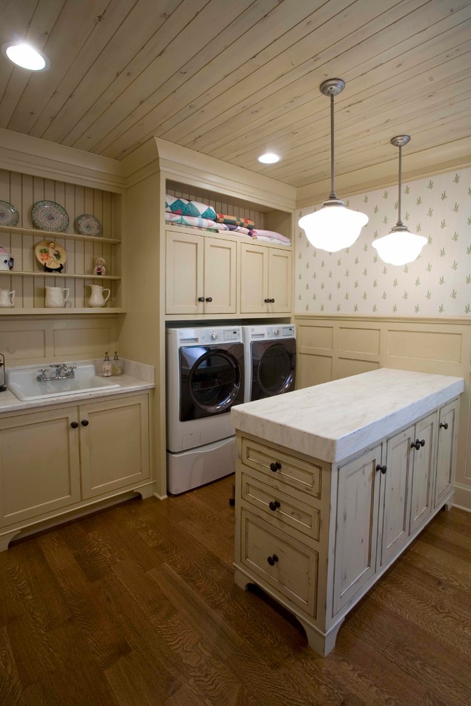 Photo of a mid-sized arts and crafts galley dedicated laundry room in Other with a drop-in sink, recessed-panel cabinets, granite benchtops, white walls, medium hardwood floors, a side-by-side washer and dryer, brown floor and beige cabinets.