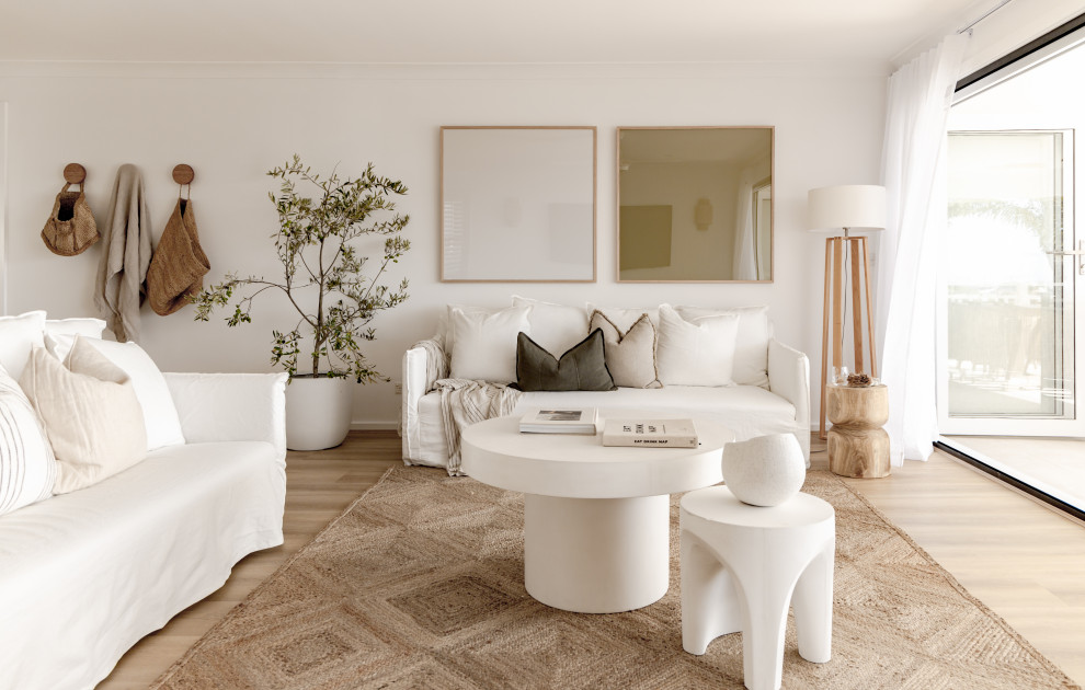 Medelhavsstil inredning av ett vardagsrum, med vita väggar, ljust trägolv och beiget golv