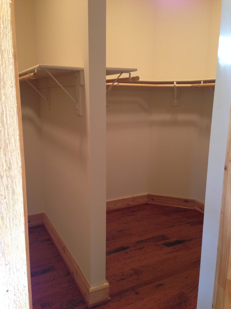 This is an example of a country gender-neutral walk-in wardrobe in Other with medium hardwood floors.