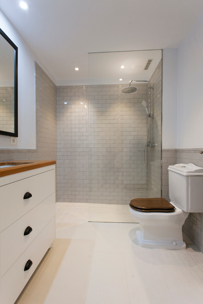 Mid-sized transitional 3/4 bathroom in Other with flat-panel cabinets, white cabinets, a curbless shower, a two-piece toilet, white walls, an undermount sink and wood benchtops.