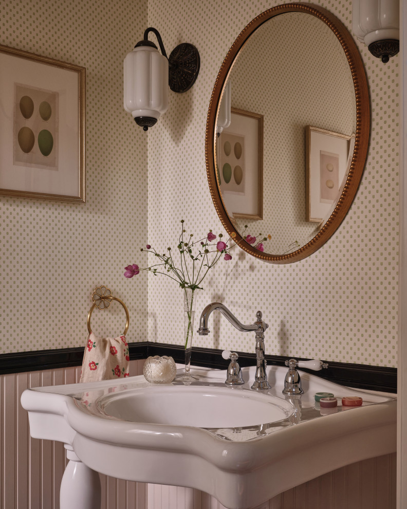 Elegant wainscoting and wallpaper powder room photo in Los Angeles with beige walls and a console sink