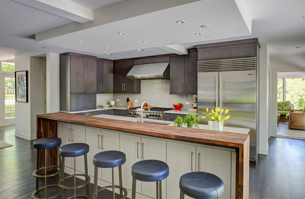 Design ideas for a large eclectic u-shaped open plan kitchen in Chicago with an undermount sink, flat-panel cabinets, beige cabinets, wood benchtops, beige splashback, stone slab splashback, stainless steel appliances, dark hardwood floors, with island and brown floor.