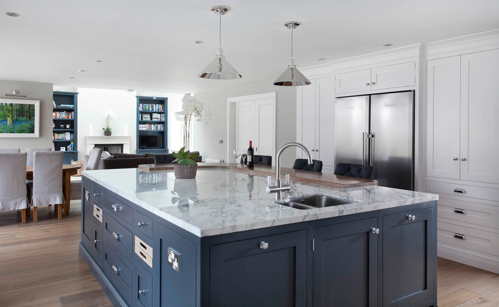 Design ideas for a large transitional u-shaped open plan kitchen in Dublin with shaker cabinets, white cabinets, marble benchtops, grey splashback, marble splashback, white appliances, medium hardwood floors, with island, brown floor and grey benchtop.