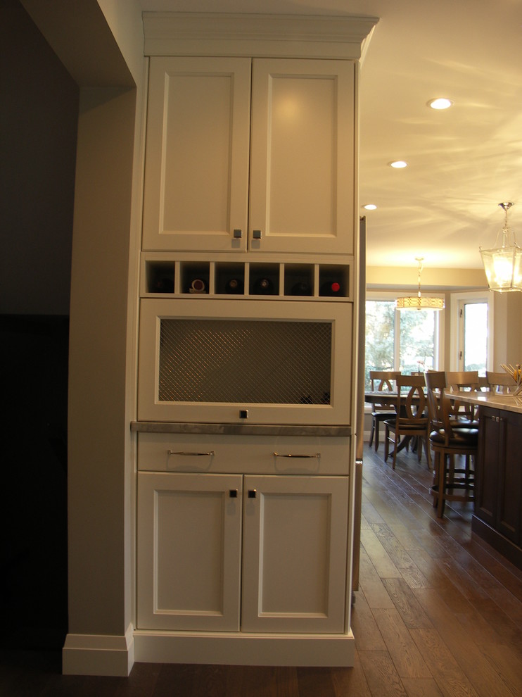 Example of a mid-sized transitional u-shaped medium tone wood floor and brown floor eat-in kitchen design in Edmonton with recessed-panel cabinets, white cabinets, an undermount sink, stainless steel appliances, an island, marble countertops, gray backsplash and matchstick tile backsplash