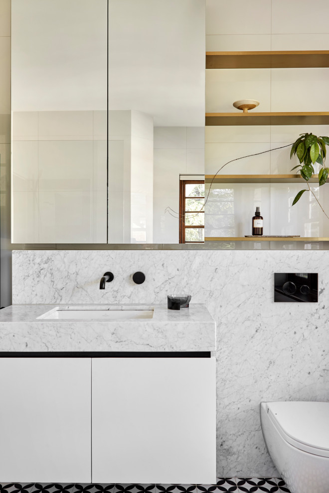Photo of a small contemporary family bathroom in Melbourne with a wall mounted toilet, white tiles, porcelain tiles, white walls, porcelain flooring, marble worktops, black floors, a single sink and a built in vanity unit.
