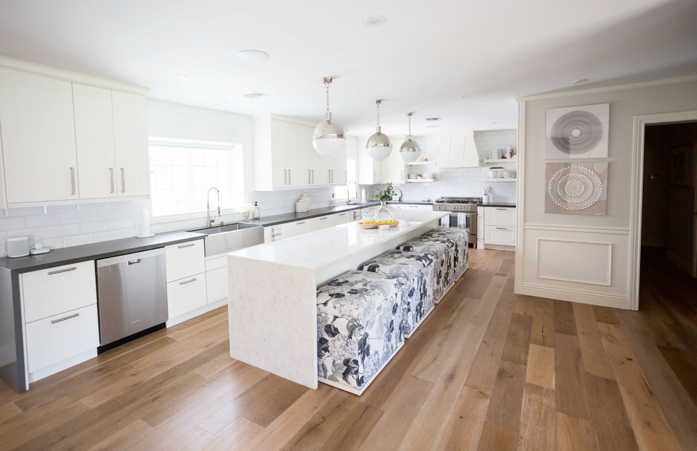 Large transitional u-shaped light wood floor and brown floor eat-in kitchen photo in Phoenix with a farmhouse sink, recessed-panel cabinets, white cabinets, quartz countertops, white backsplash, subway tile backsplash, stainless steel appliances, an island and white countertops
