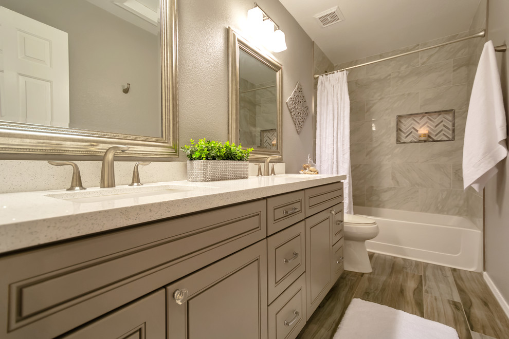Mid-sized transitional kids' gray tile and porcelain tile porcelain tile and gray floor alcove bathtub photo in Phoenix with raised-panel cabinets, gray cabinets, gray walls, a drop-in sink, quartz countertops and white countertops