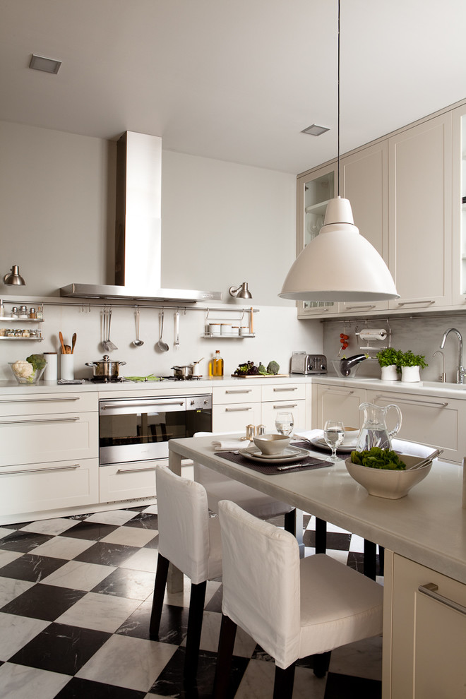 This is an example of a mid-sized transitional u-shaped separate kitchen in Barcelona with recessed-panel cabinets, white cabinets, white splashback, stainless steel appliances, ceramic floors and no island.