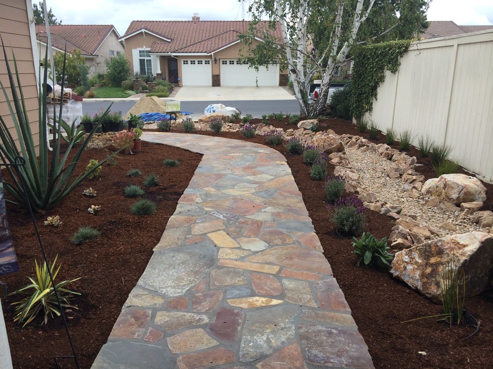 Inspiration for a mid-sized traditional front yard full sun xeriscape for spring in Los Angeles with natural stone pavers.