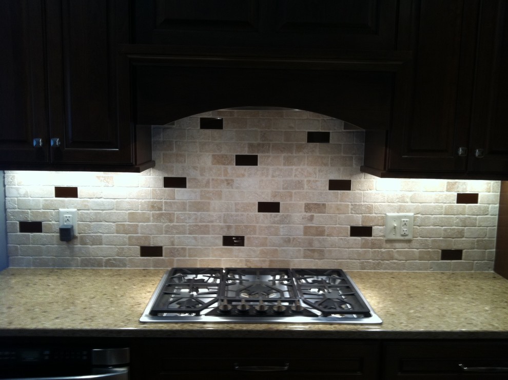 Eat-in kitchen - mid-sized traditional single-wall eat-in kitchen idea in Chicago with recessed-panel cabinets, black cabinets, granite countertops, beige backsplash, stone tile backsplash and stainless steel appliances