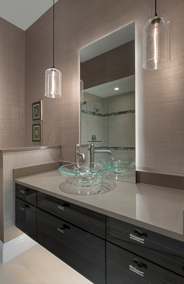 Photo of a mid-sized asian powder room in Miami with a vessel sink, furniture-like cabinets, dark wood cabinets, beige tile, porcelain floors and a one-piece toilet.