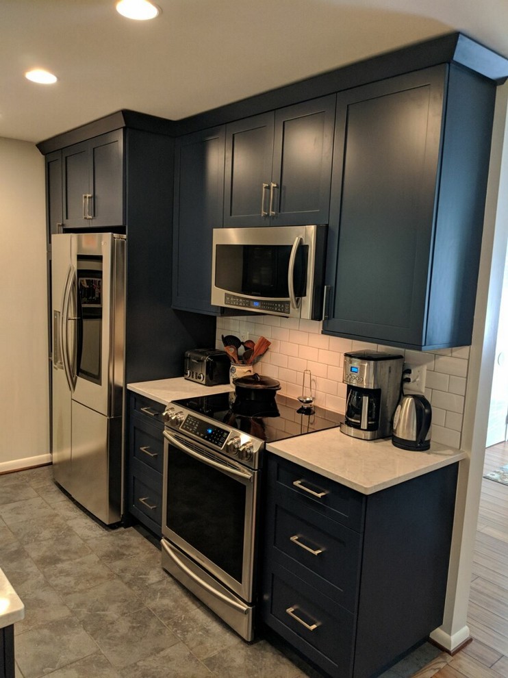 Design ideas for a small transitional galley kitchen in DC Metro with a single-bowl sink, flat-panel cabinets, blue cabinets, quartz benchtops, white splashback, ceramic splashback, stainless steel appliances, porcelain floors, no island, grey floor and white benchtop.