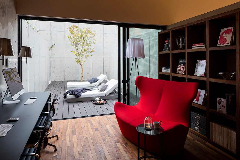 Industrial study room in Tokyo with grey walls, medium hardwood floors and a freestanding desk.