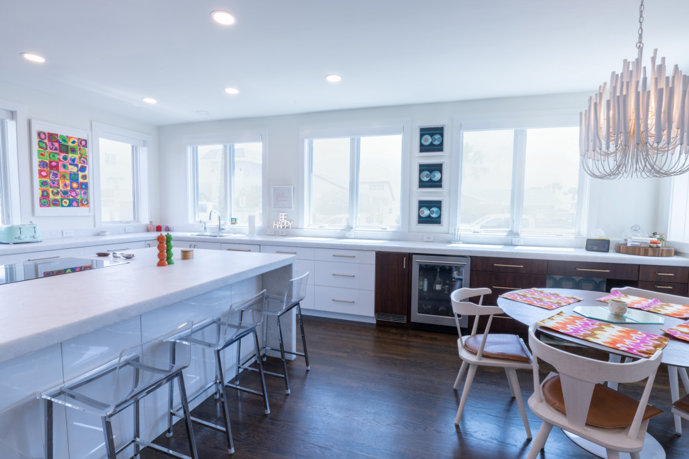 Foto di una cucina minimalista con lavello da incasso, ante lisce, ante in legno bruno, elettrodomestici da incasso, parquet scuro, pavimento marrone e top bianco