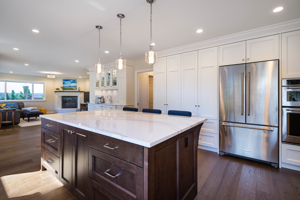 Example of a large transitional u-shaped medium tone wood floor and brown floor eat-in kitchen design in Vancouver with an undermount sink, recessed-panel cabinets, white cabinets, quartz countertops, white backsplash, mosaic tile backsplash, stainless steel appliances and an island