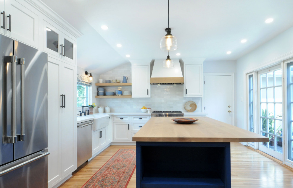 Example of a mid-sized french country l-shaped eat-in kitchen design in Los Angeles with a farmhouse sink, white cabinets, quartz countertops, white backsplash and an island