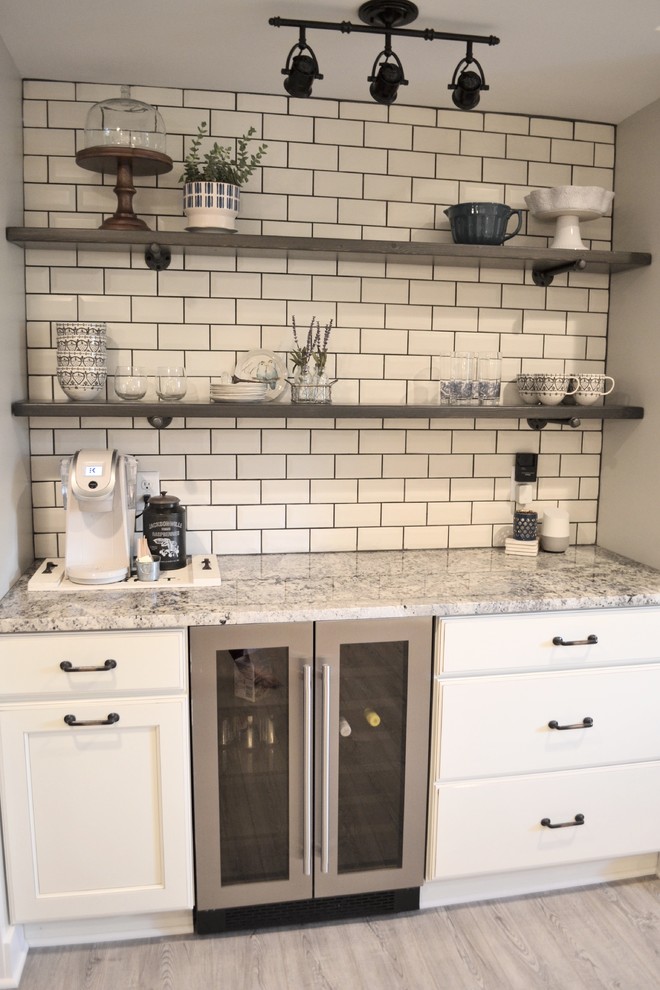 This is an example of a small country single-wall home bar in Detroit with no sink, shaker cabinets, beige cabinets, granite benchtops, beige splashback, subway tile splashback and vinyl floors.