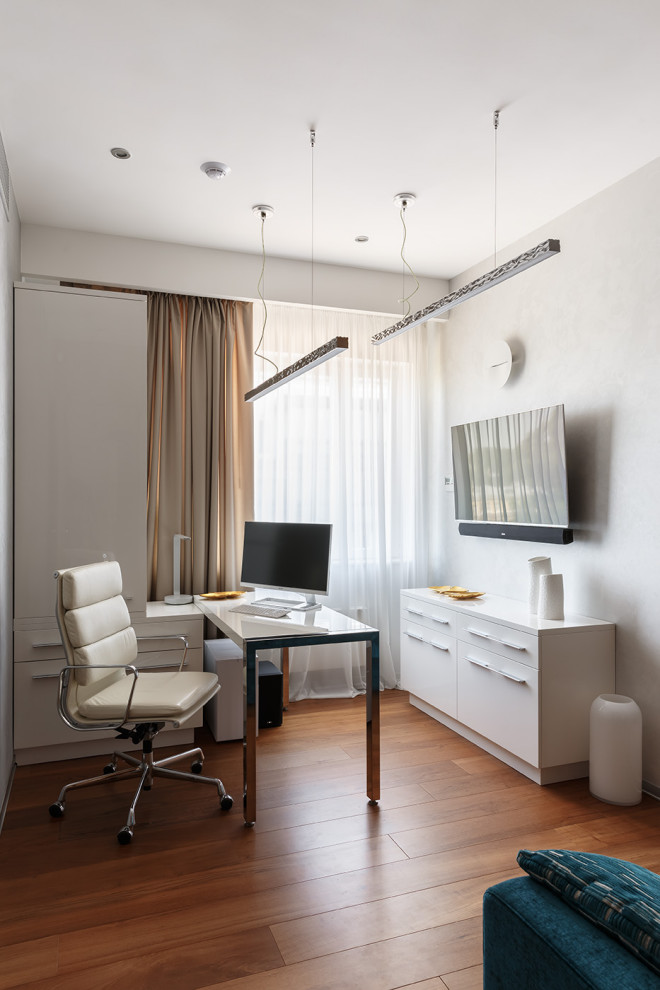 Kleines Modernes Arbeitszimmer mit Arbeitsplatz, grauer Wandfarbe, braunem Holzboden, freistehendem Schreibtisch, braunem Boden und Wandpaneelen in Sankt Petersburg