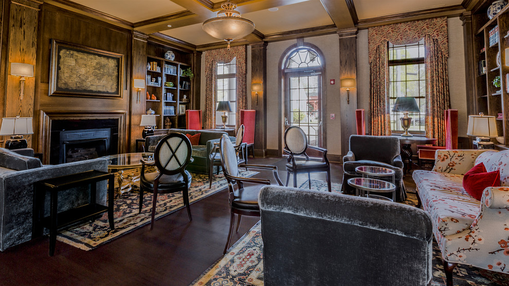 Home office library - large rustic dark wood floor home office library idea with a standard fireplace and a wood fireplace surround