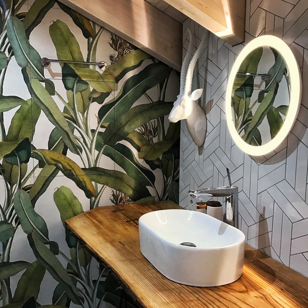 Photo of a mid-sized industrial powder room in Moscow with a wall-mount toilet, white tile, glass tile, grey walls, ceramic floors, a drop-in sink, wood benchtops, white floor and beige benchtops.