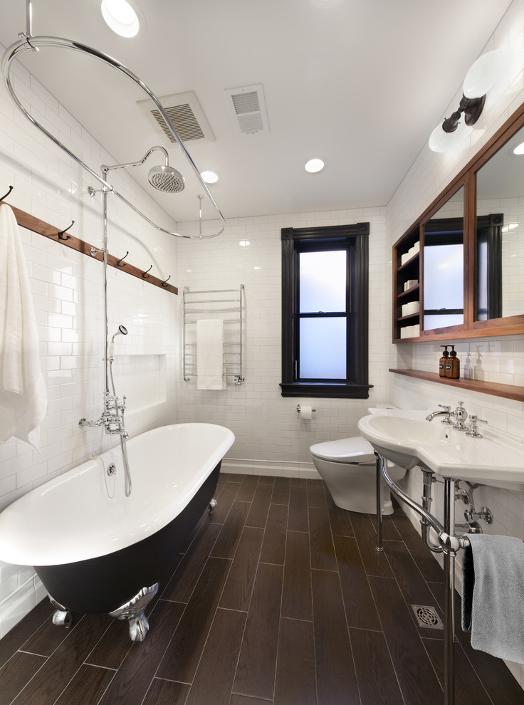 Inspiration for a mid-sized transitional master subway tile and white tile porcelain tile and black floor claw-foot bathtub remodel in DC Metro with white walls, open cabinets, medium tone wood cabinets, a one-piece toilet and a console sink