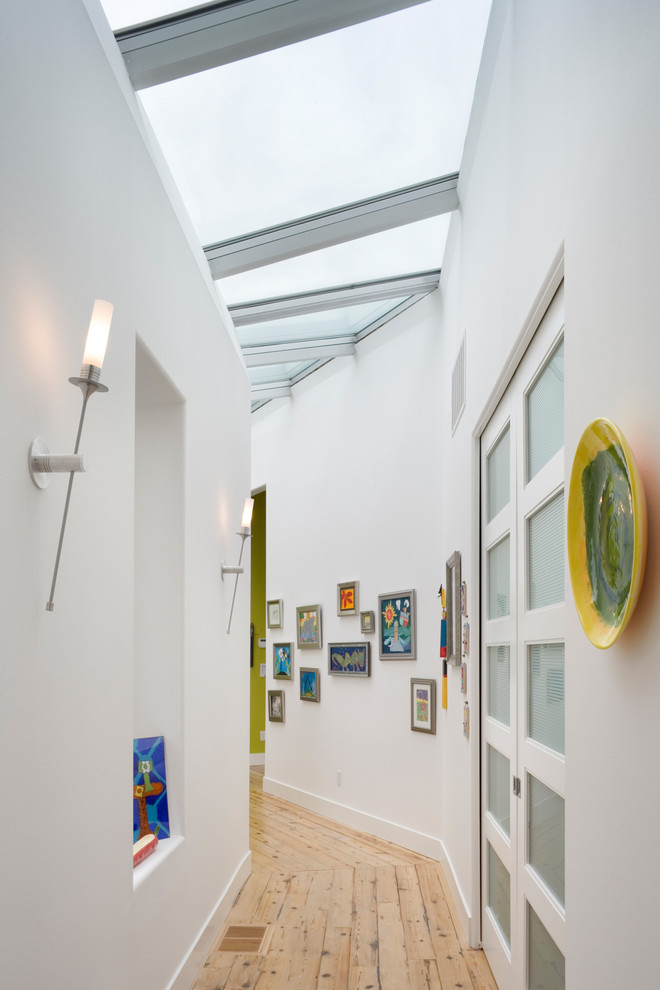 Photo of a contemporary hallway in Portland with white walls and light hardwood floors.
