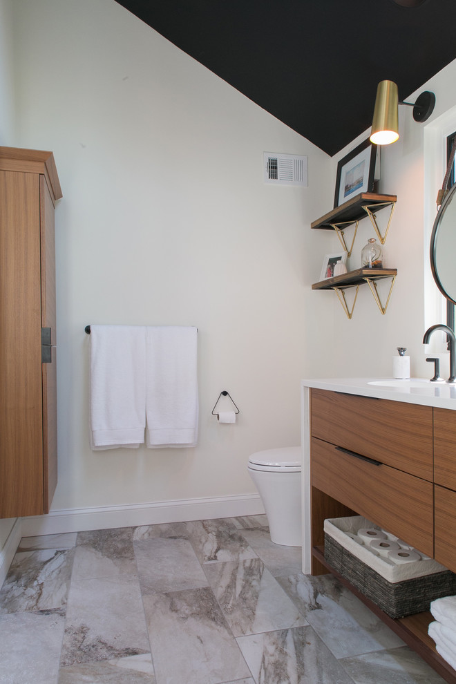 Inspiration for a mid-sized transitional master bathroom in Philadelphia with flat-panel cabinets, medium wood cabinets, a corner shower, a one-piece toilet, white tile, subway tile, white walls, porcelain floors, an undermount sink, engineered quartz benchtops, multi-coloured floor and a hinged shower door.