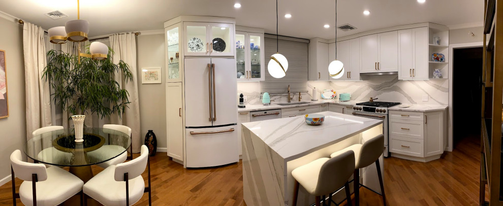Photo of a mid-sized transitional l-shaped eat-in kitchen in New York with an undermount sink, shaker cabinets, white cabinets, quartz benchtops, white splashback, engineered quartz splashback, white appliances, dark hardwood floors, with island, brown floor and white benchtop.