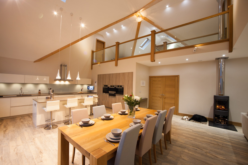 Photo of a contemporary kitchen/diner in Other with a submerged sink, flat-panel cabinets, white cabinets, white splashback, glass sheet splashback, medium hardwood flooring and an island.