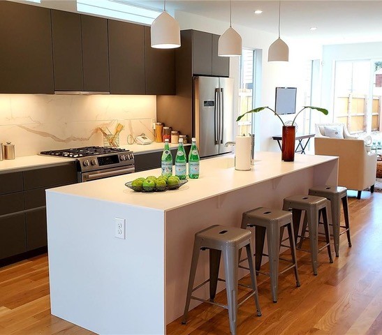 Mid-sized minimalist galley medium tone wood floor and brown floor open concept kitchen photo in Denver with an undermount sink, flat-panel cabinets, dark wood cabinets, quartz countertops, white backsplash, porcelain backsplash, stainless steel appliances, an island and white countertops